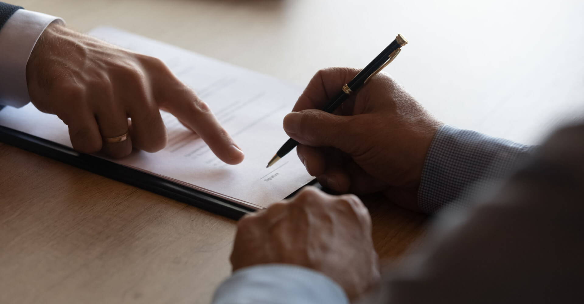 Hands of lawyer pointing at paper for businessman signing contract. Solicitor, legal advisor helping mature client to fill up document, medical insurance form, will, affixing signature. Paperwork